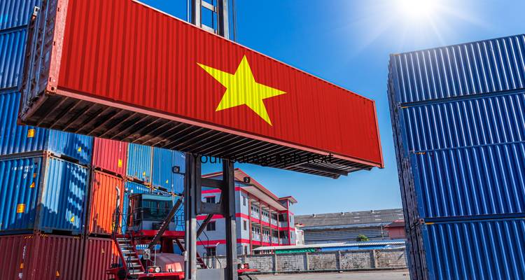 Shipping container painted with Vietnam flag being lifted in a sunny freight yard