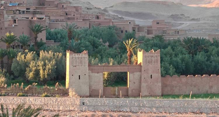 Adobe gate flanked by palm groves and mud-brick homes near Ouarzazate.