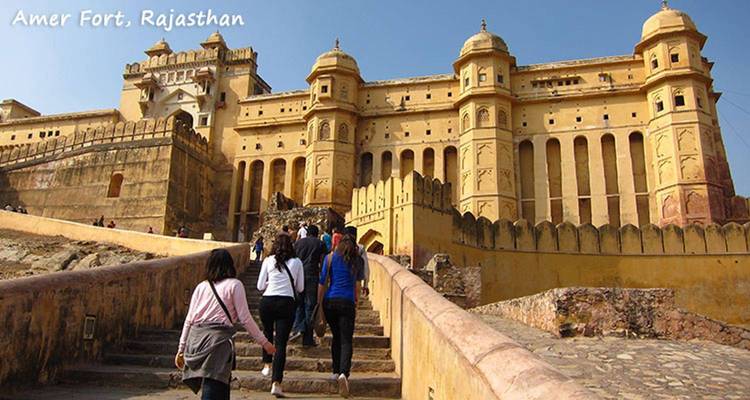 Visitors climb stone steps toward the yellow ramparts of Amer Fort in Rajasthan.