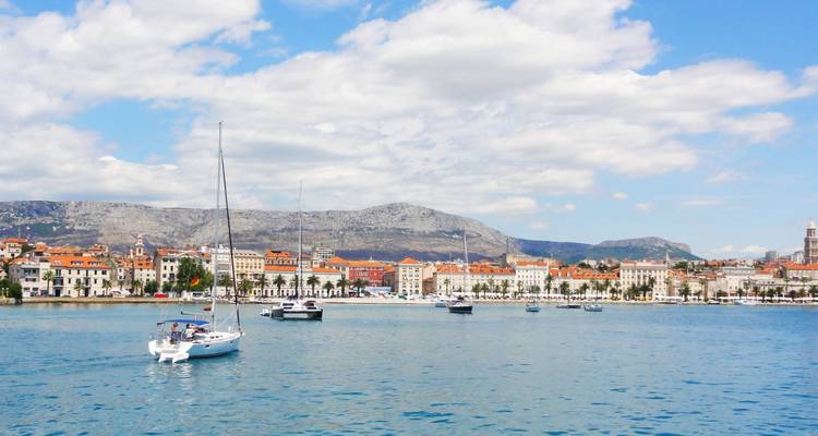 Panorama côtier de Split avec des voiliers naviguant sur les eaux bleues et calmes sous la ligne d'horizon de la ville.