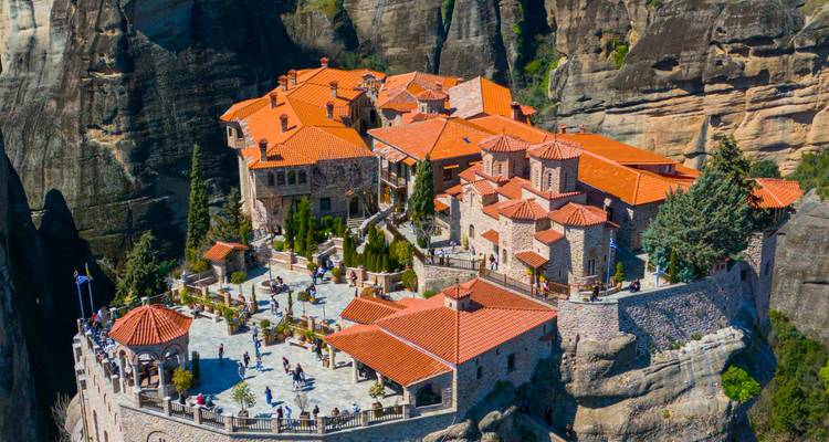 Monastère spectaculaire aux toits de tuiles rouges perché au sommet de hauts piliers rocheux à Meteora