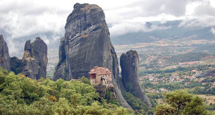 Monastère isolé niché parmi des formations rocheuses verticales spectaculaires sous un ciel nuageux