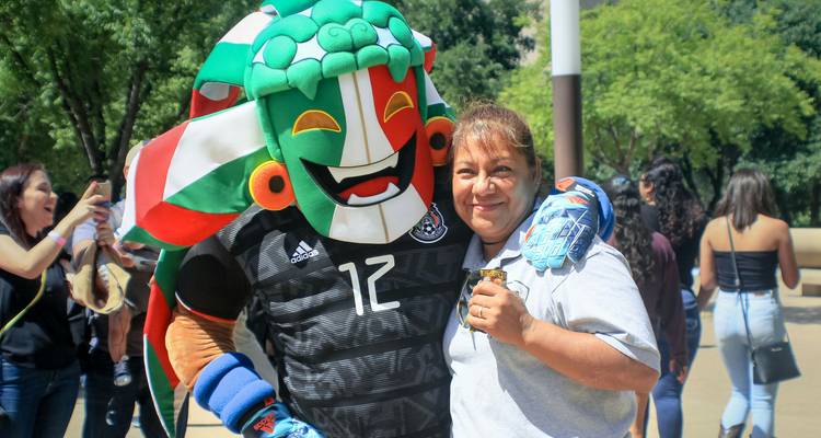 Femme souriante serrant dans ses bras une mascotte de football colorée dans un parc