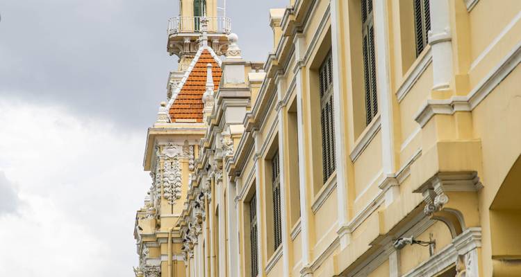 Edificio de estilo colonial amarillo con una torre ornamentada contra un cielo nublado.
