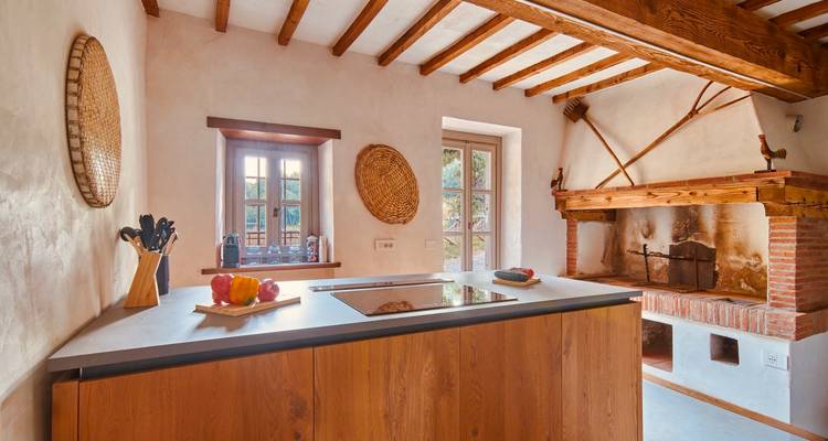Rustic yet modern kitchen with wooden island, beamed ceiling, brick fireplace and soft natural light