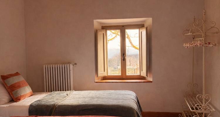 Simple bedroom with twin beds and a window view over wintry trees and distant hills