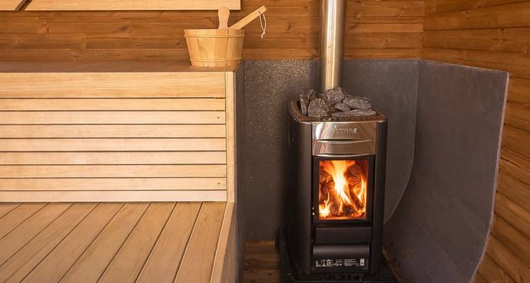 Warm wooden sauna interior with bucket, ladle and fire burning in a stove