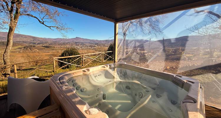 Outdoor hot tub under a canopy overlooking rolling valleys and distant mountains