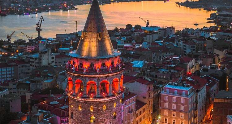 Galata Tower illuminated in warm colors overlooking Istanbul at twilight