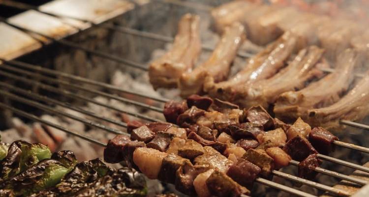 Close-up of assorted meats and vegetables grilling over hot coals.