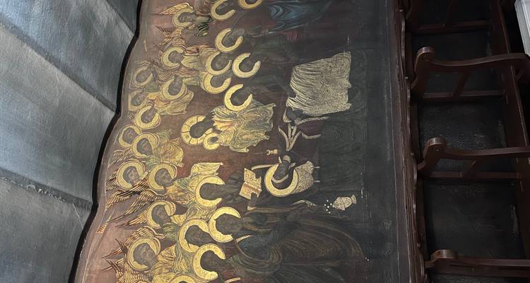 Mural interior que representa santos con halos dorados en una capilla débilmente iluminada.