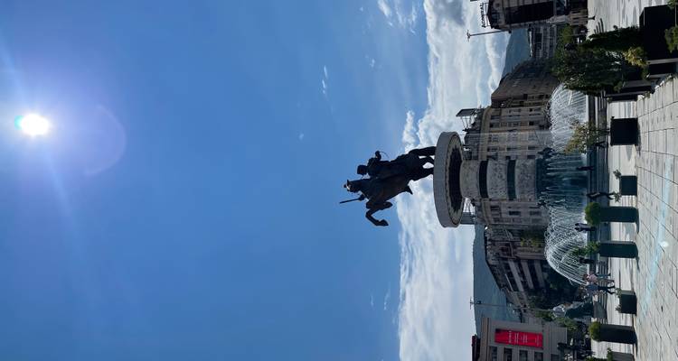 Fuente de la plaza central con una estatua ecuestre recortada contra el brillante sol del mediodía.