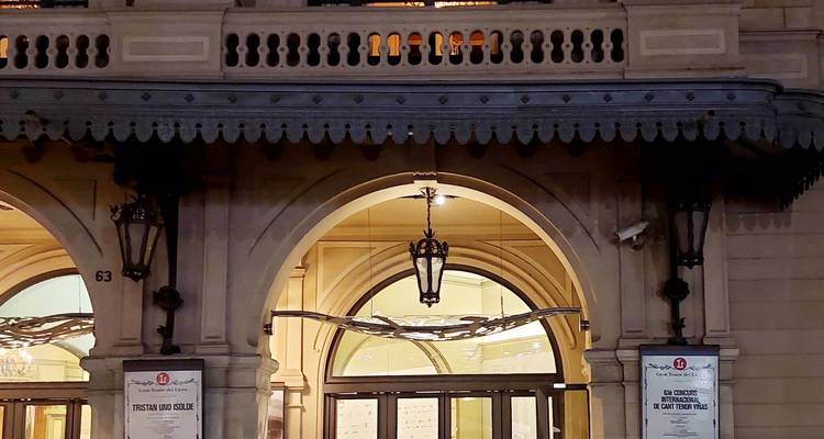 Elegante entrada del teatro con arcos, linternas colgantes y carteles de eventos.