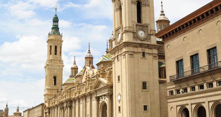 Elegant baroque basilica with ornate bell-towers and clock against a blue sky in an historic city centre.