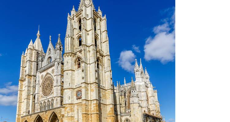 Tall vertical view of León Cathedral spires set against deep blue sky, image cropped with blank side.