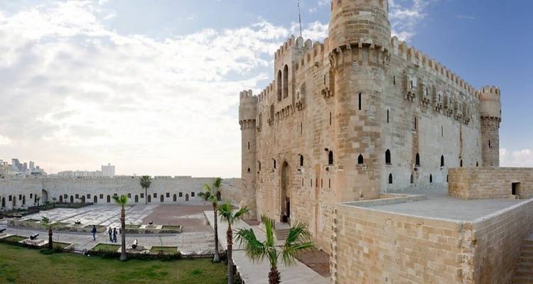 Los muros de piedra y torres de la Ciudadela de Qaitbay se mantienen firmes contra un cielo brillante.