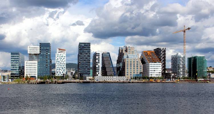 Le skyline distinctif en code-barres d'Oslo s'élevant au-dessus du fjord sous un ciel partiellement nuageux