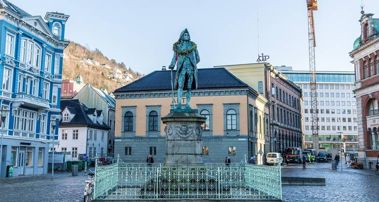 Fontaine couronnée d'une statue dans une place pavée entourée de bâtiments historiques de Bergen.
