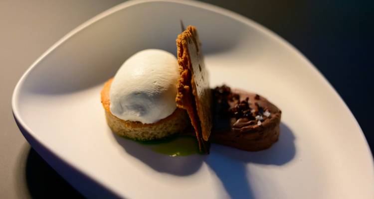 Gourmet dessert with ice-cream quenelle and chocolate mousse on a white plate