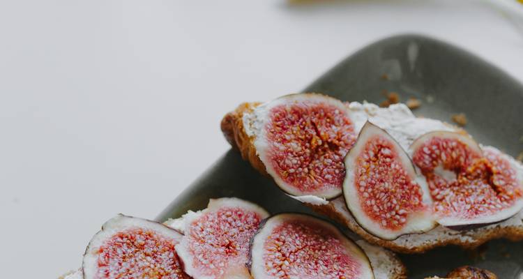 Toast with ripe fig slices and creamy spread on minimalist background