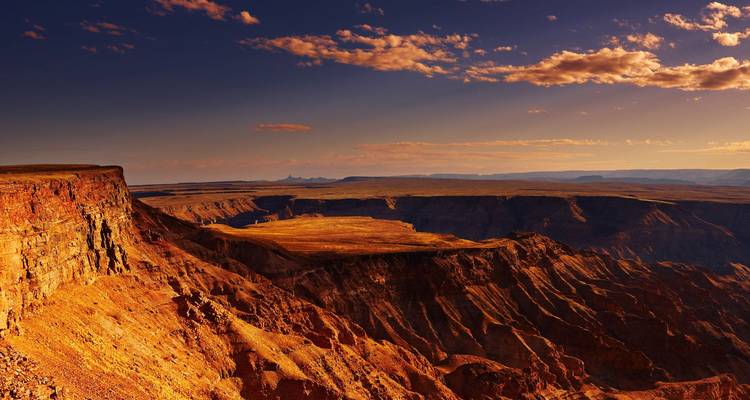 Rugged, reddish canyon landscape bathed in warm late-day sunlight.
