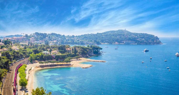 Panorama côtier avec des criques de sable, des eaux turquoise et une péninsule boisée près de Nice.