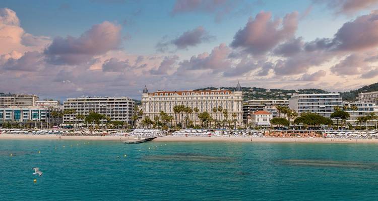 Boulevard élégant en bord de mer à Cannes avec de grands hôtels donnant sur une baie bleue calme.