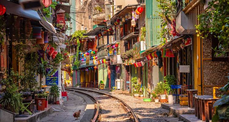 Colourful houses and cafés lining the narrow Hanoi Train Street with railway tracks in foreground