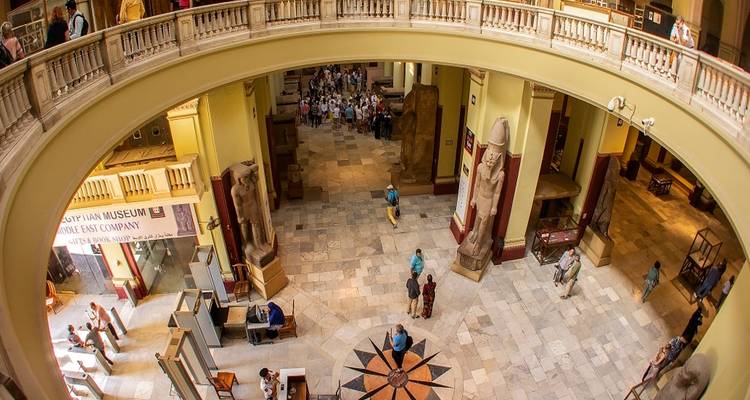 Wide fisheye interior shot of the Egyptian Museum with visitors walking among statues and artifacts.