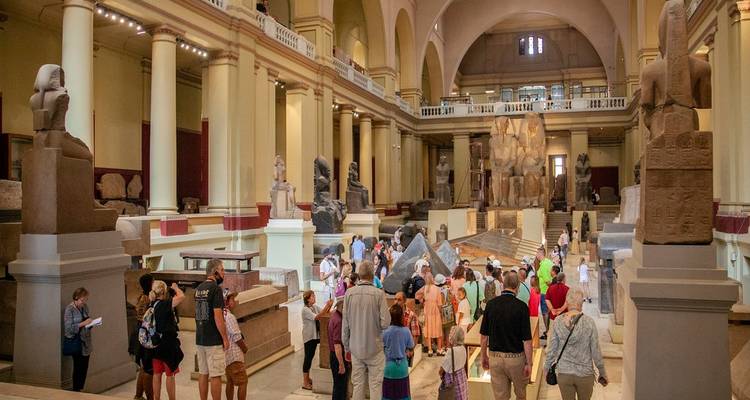 Visitors exploring a hall filled with ancient Egyptian statues and sarcophagi inside the museum.