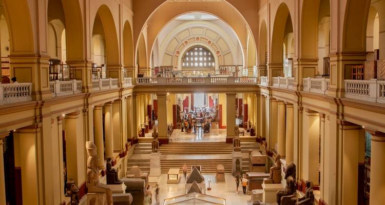 Grand central gallery of the Egyptian Museum with high arches and scattered ancient artifacts.
