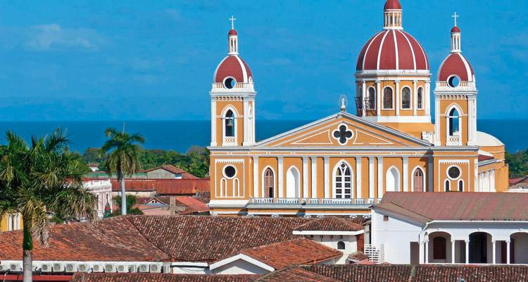 Ikonische gelbe und rote Kathedrale mit Doppelkuppeln, die sich über die Ziegeldächer von Granada erheben.