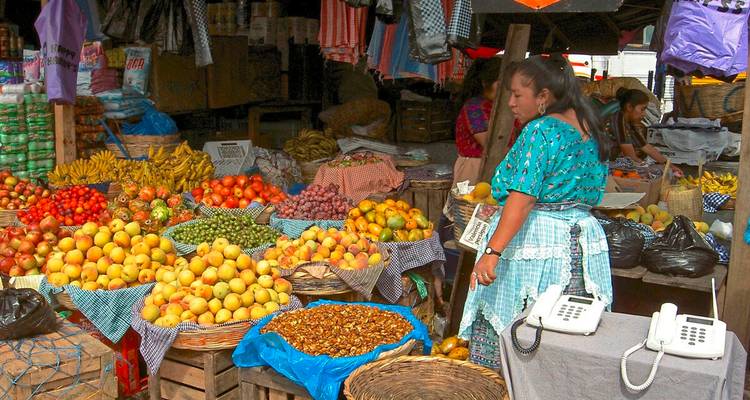 Lebendiger Freiluftmarktstand, der mit tropischen Früchten und Gemüse gefüllt ist, während Verkäufer die Waren sortieren.