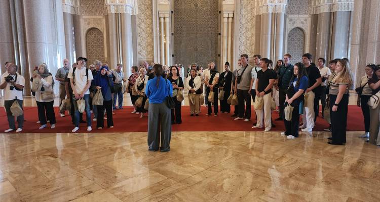 A guide addresses a tour group inside the vast marble prayer hall of the Hassan II Mosque.