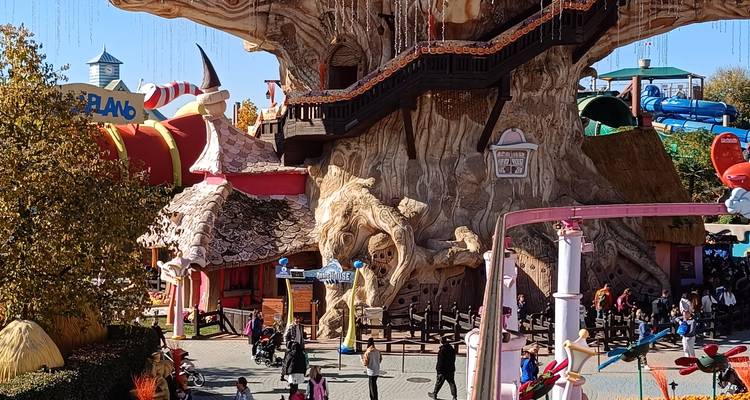 Atracción de casa del árbol de cuento de hadas colorida llena de visitantes en el parque temático Gardaland