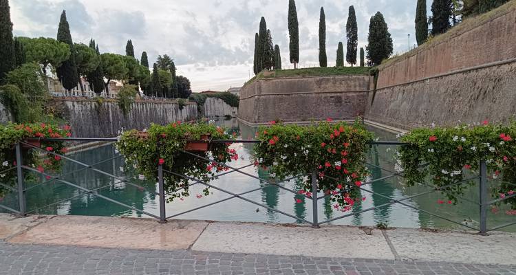 Bastiones del canal de Peschiera decorados con flores rojas en flor en barandillas de hierro