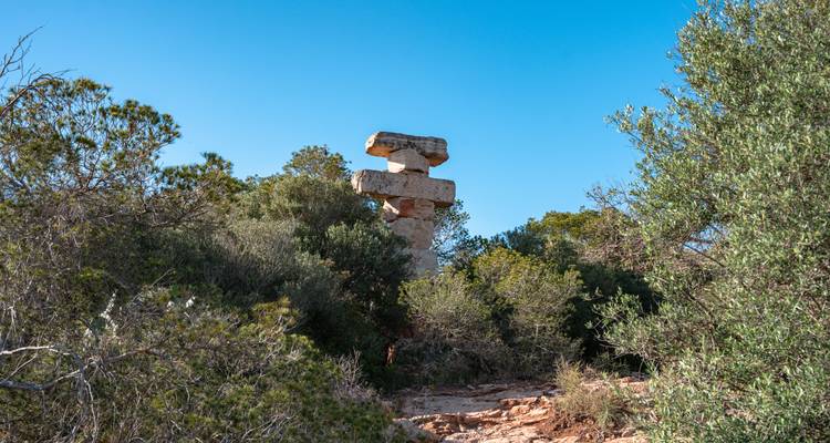 Pile de piliers en pierre s'élevant au-dessus de la broussaille et des arbustes méditerranéens