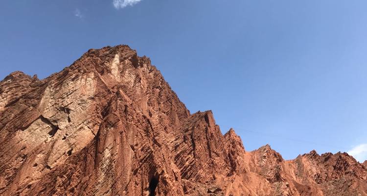 Steep red sandstone cliffs rising under a bright sky, highlighting desert geology.