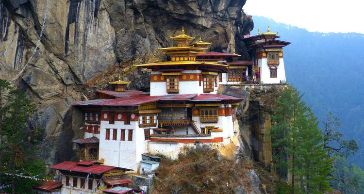 Le monastère du Nid du Tigre s'accrochant spectaculairement à la paroi d'une falaise surplombant une vallée boisée au Bhoutan.