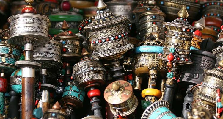 Assortiment en gros plan de roues de prière tibétaines ornées et d'objets rituels en métal et turquoise.