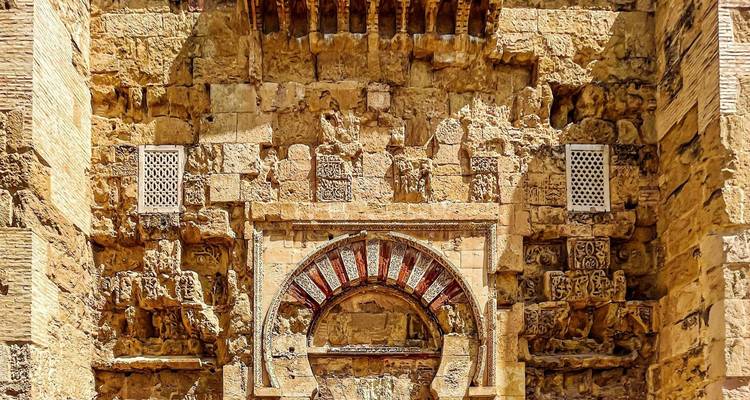 Primer plano de un arco morisco ornamentado y tallas de piedra intrincadas en el interior de la Mezquita de Córdoba.