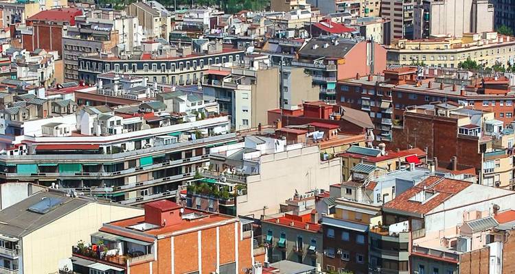 Dichtes Mosaik aus Wohngebäudedächern und Terrassen, das das Stadtgefüge Barcelonas prägt.