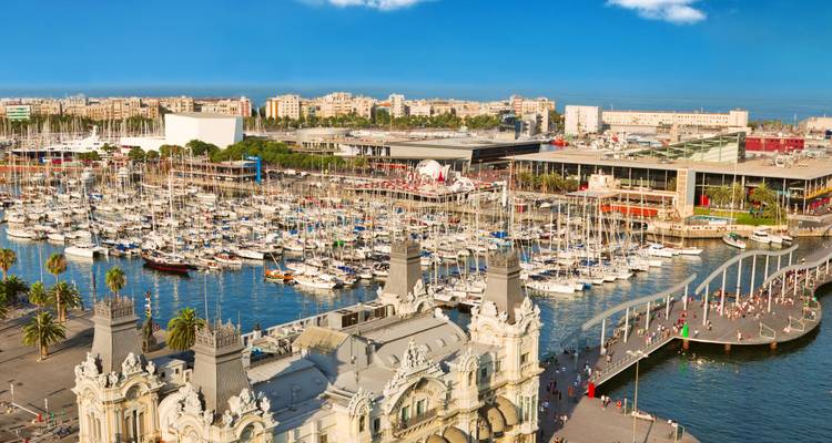 Panoramablick über Barcelonas Hafen Port Vell mit Yachten und einer belebten Uferlandpromenade.