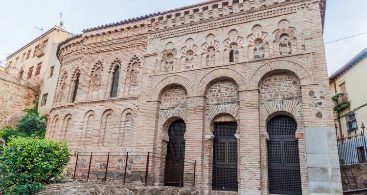 Iglesia de estilo mudéjar con ladrillo y ventanas arqueadas en el barrio histórico de Toledo.