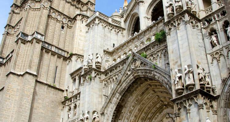 Los portales góticos ornamentados y los arbotantes volantes de la Catedral de Toledo capturados desde un ángulo bajo.