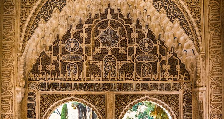 Gedetailleerde Moorse stucco patronen boven dubbele bogen in het Alhambra.