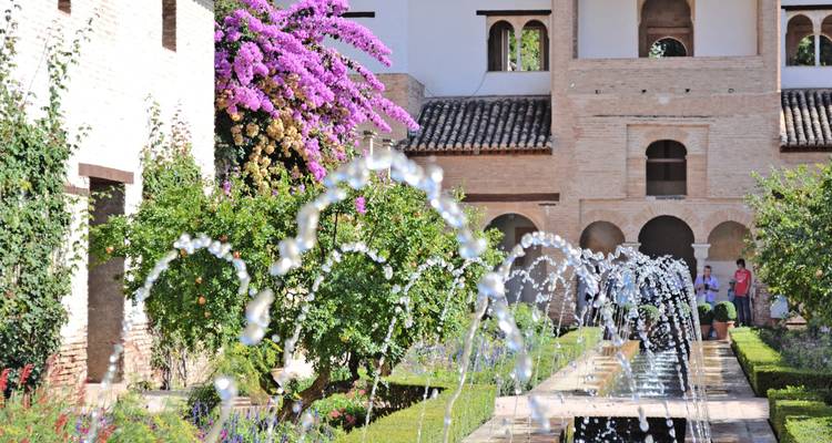 Waterfonteinen die glinsteren in het Generalife-binnenplein met bloeiende bougainvillea.