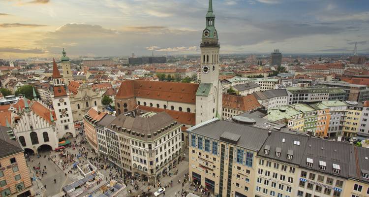 Vista elevada de la Marienplatz de Munich con multitudes, iglesias históricas y tejados al atardecer