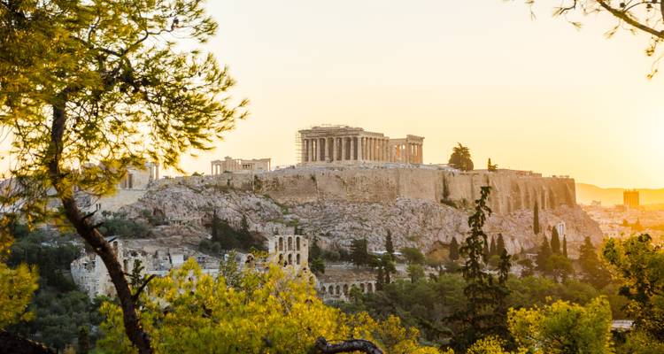 Golden hour view of the Acropolis hill and Parthenon bathed in warm light above Athens