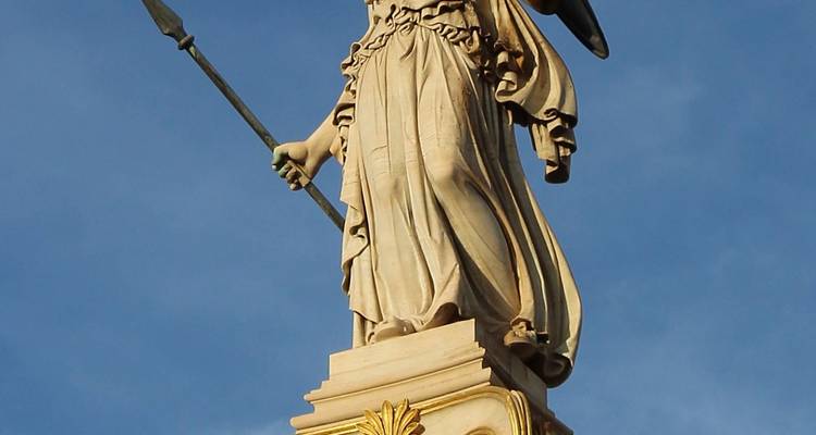 Close-up of a marble Athena statue holding spear beneath a clear blue sky